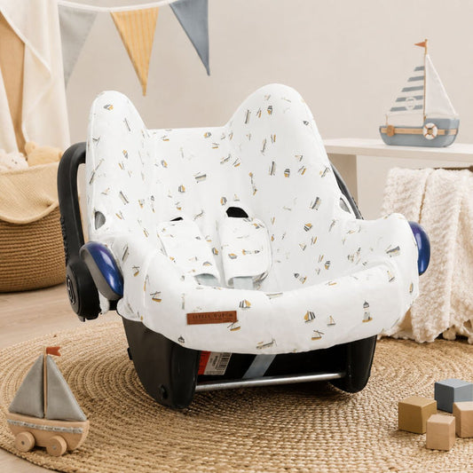 Weißer Babyschalenbezug mit maritimem Design auf einer Maxi-Cosi Babyschale in einem gemütlichen Babyzimmer – weicher Baumwollbezug für Babyschalen der Gruppe 0+.