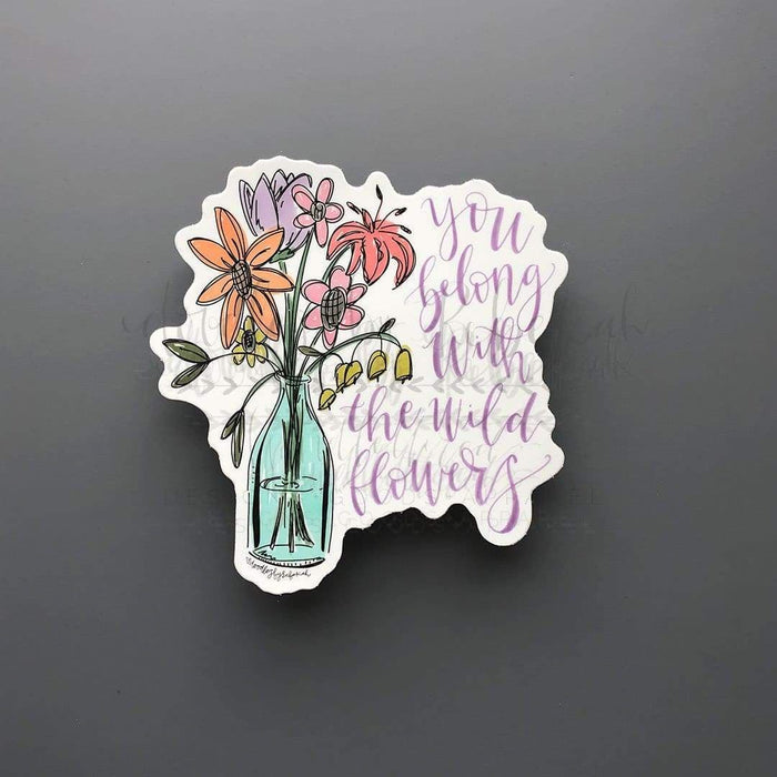 a sticker with the phrase "you belong with the wild flowers" and a hand drawn bouquet